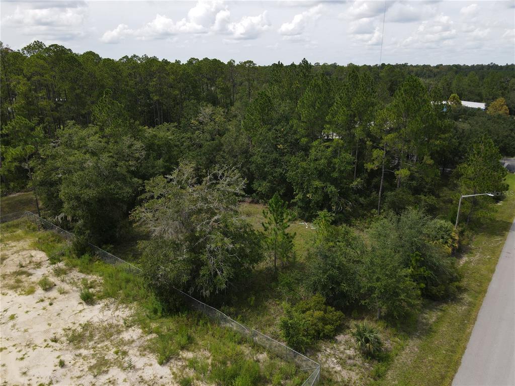 An aerial view shows a wooded, undeveloped lot bordered by a road and a chain-link fence — LOT 4 & LOT 5 NW 16TH STREET, GAINESVILLE, FL