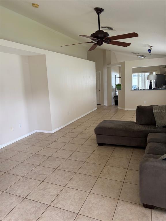 A living room with tile flooring, a ceiling fan, and a large sectional sofa — 24312 SILKBAY COURT, LUTZ, FL