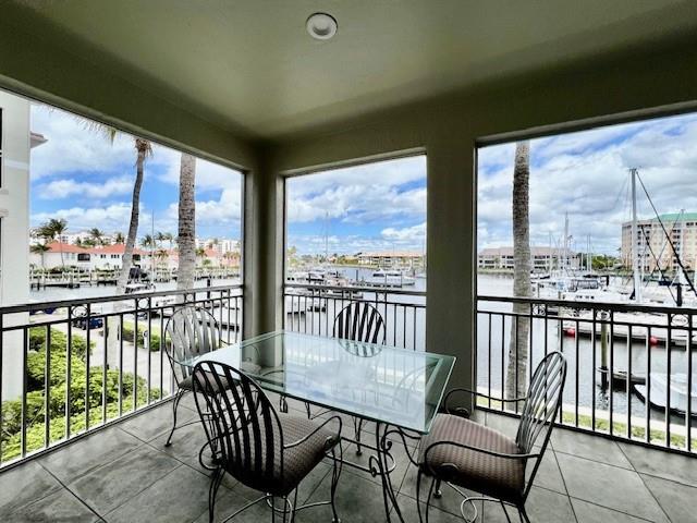 A screened balcony features a glass dining table, four chairs, and a view of a marina — 3471 SUNSET KEY CIRCLE UNIT 102, PUNTA GORDA, FL