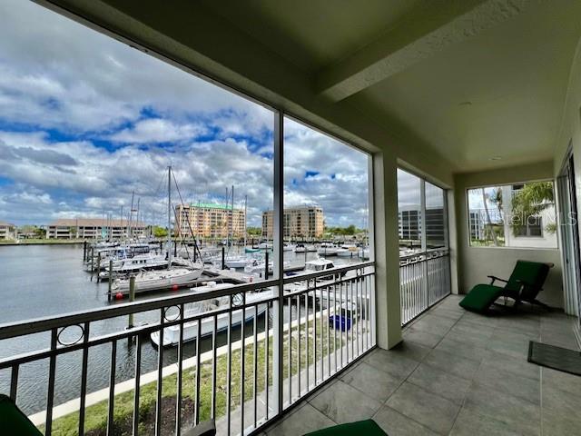 A screened-in balcony overlooking a marina with boats and multi-story buildings under a cloudy sky — 3471 SUNSET KEY CIRCLE UNIT 102, PUNTA GORDA, FL