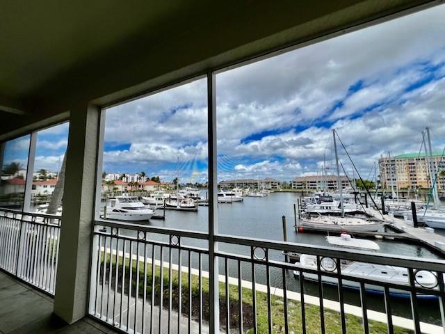 A screened-in balcony overlooks a marina filled with various boats under a cloudy sky — 3471 SUNSET KEY CIRCLE UNIT 102, PUNTA GORDA, FL