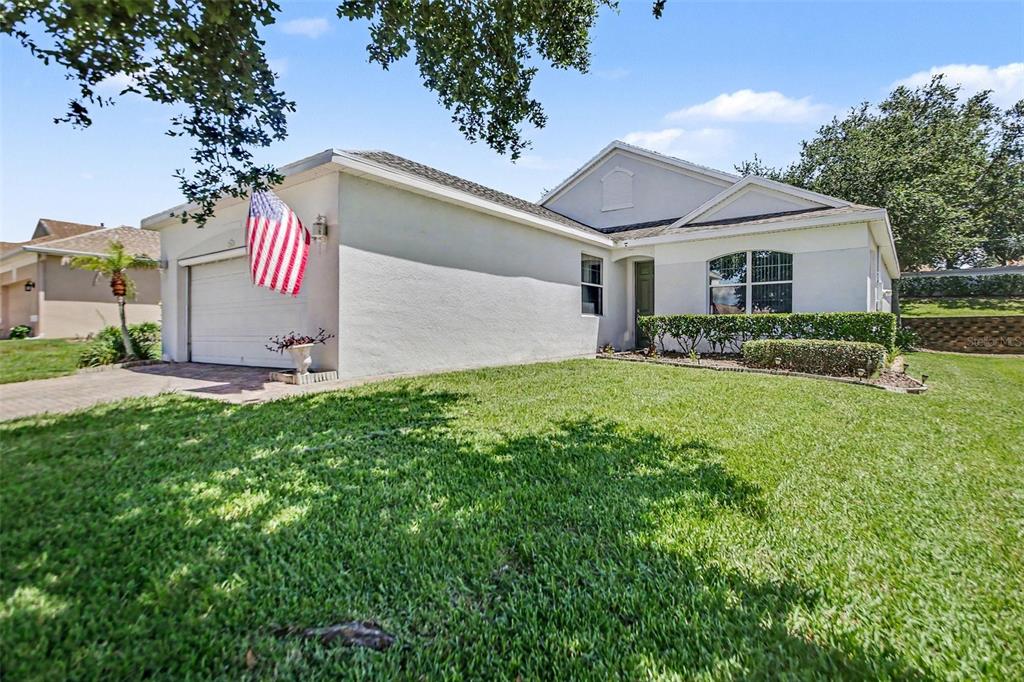 A living room with wood-look flooring, a large area rug, and a vaulted ceiling — 2361 PRAIRIE DUNES, CLERMONT, FL