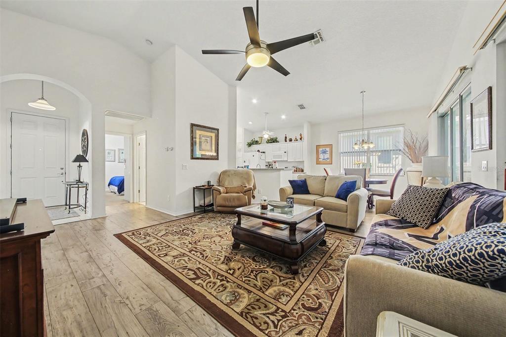A living room features a vaulted ceiling, a ceiling fan, and a large television console — 2361 PRAIRIE DUNES, CLERMONT, FL