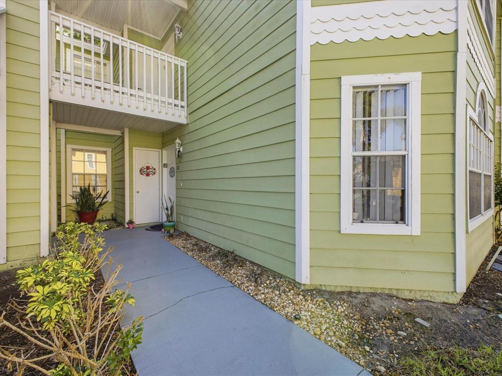 A light green two-story building exterior features a concrete walkway leading to a white door — 3153 BRITANNIA BOULEVARD UNIT B, KISSIMMEE, FL