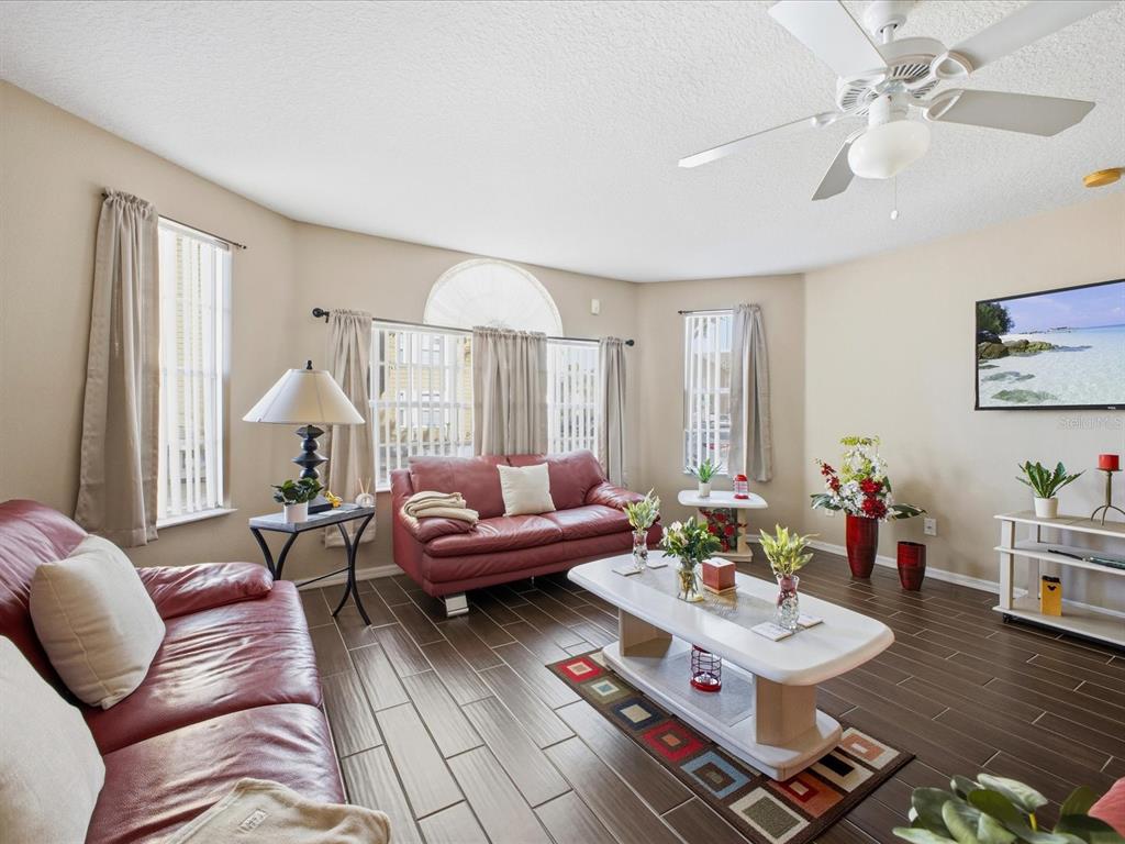 A living room features red leather sofas, a white coffee table, and dark tile flooring — 3153 BRITANNIA BOULEVARD UNIT B, KISSIMMEE, FL