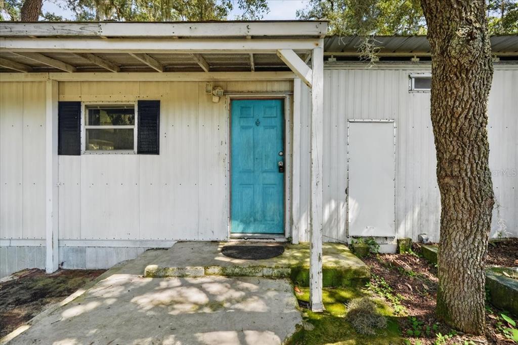 The exterior of a mobile home features a bright blue door and a concrete porch — 12489 SW 45TH TERRACE, WEBSTER, FL