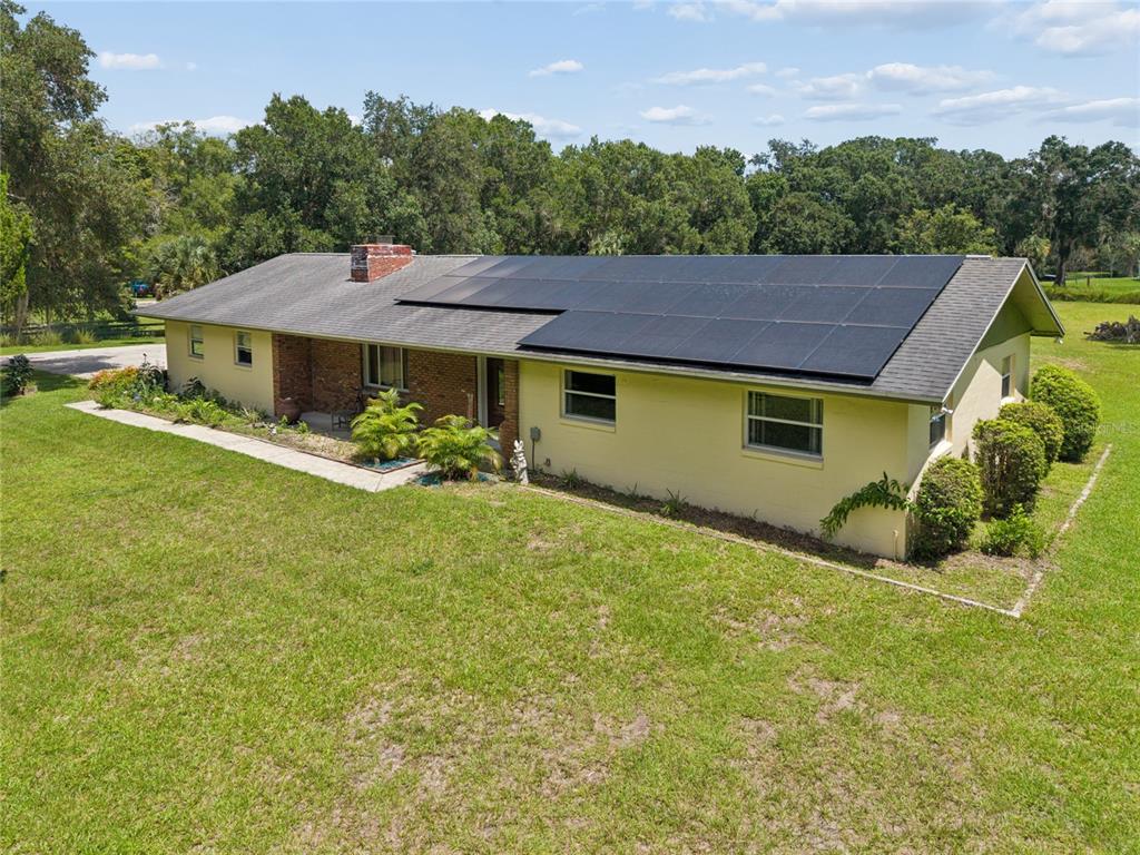 An exterior view of a single-story yellow house with a solar panel array on the roof — 4285 SHAMROCK DRIVE, MIMS, FL