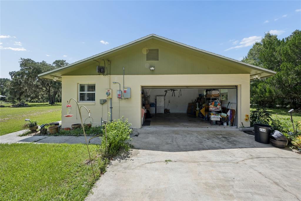 A detached garage with an open bay, concrete driveway, and light-colored exterior walls — 4285 SHAMROCK DRIVE, MIMS, FL