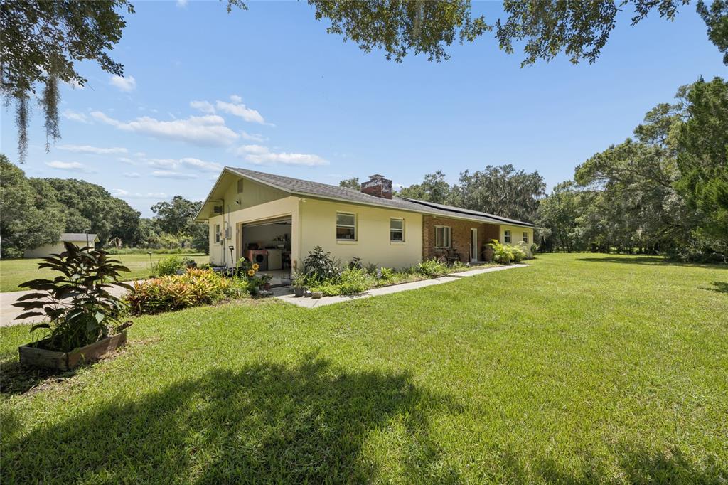 A single-story house with a garage and brick accents sits on a large grassy lot — 4285 SHAMROCK DRIVE, MIMS, FL