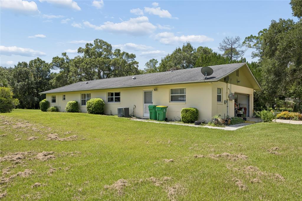 A single-story house with a light-colored exterior, a garage, and a large grassy yard — 4285 SHAMROCK DRIVE, MIMS, FL