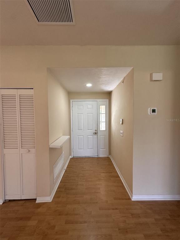 An entryway features light-colored walls, wood-look flooring, a white front door, and a closet — 35 MAGNOLIA AVENUE UNIT 35, ORMOND BEACH, FL