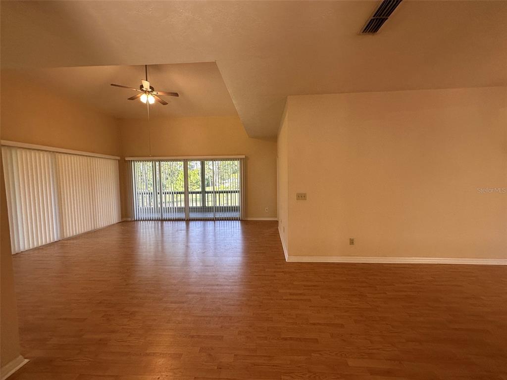 A spacious living room features light wood-look flooring, a vaulted ceiling, and large sliding doors — 35 MAGNOLIA AVENUE UNIT 35, ORMOND BEACH, FL