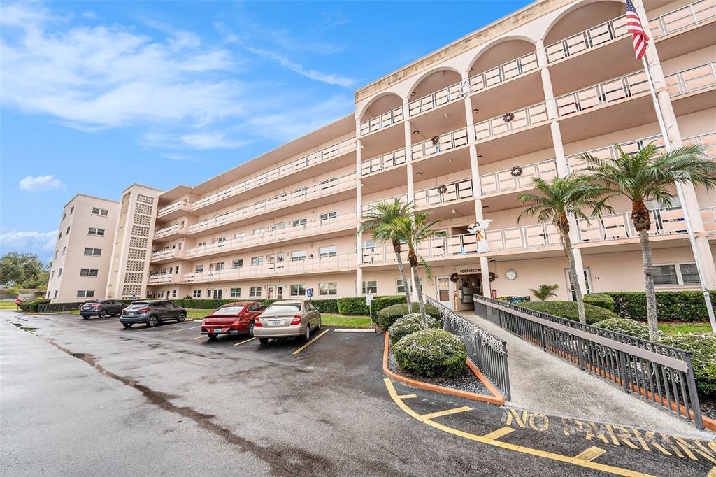A multi-story apartment building features a parking lot, palm trees, and a wheelchair ramp — 5623 80TH STREET N UNIT 211, ST PETERSBURG, FL
