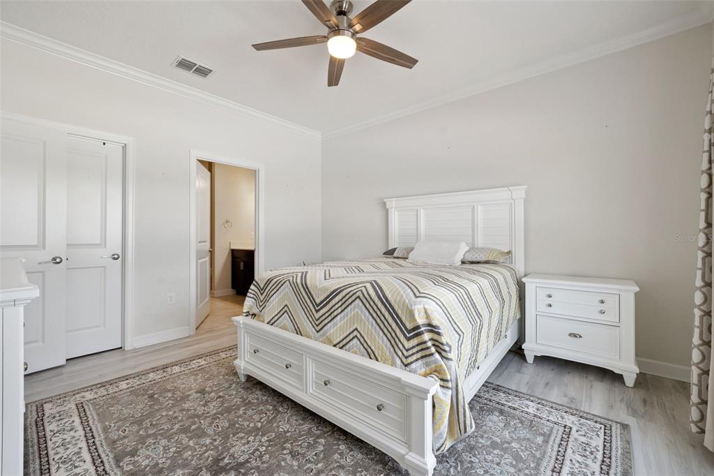 A bedroom features a white bed frame, a patterned comforter, and a ceiling fan — 3569 BELLAND CIRCLE UNIT C, CLERMONT, FL