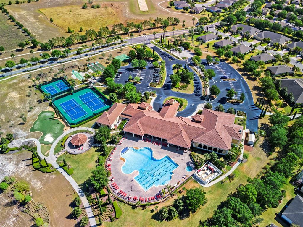 Aerial view of a community clubhouse featuring a swimming pool, tennis courts, and parking lot — 3569 BELLAND CIRCLE UNIT C, CLERMONT, FL