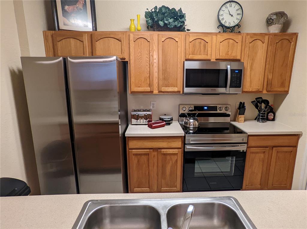 A kitchen features wood cabinets, stainless steel appliances, and a double-basin sink — 2817 ALMATON LOOP UNIT 304, KISSIMMEE, FL