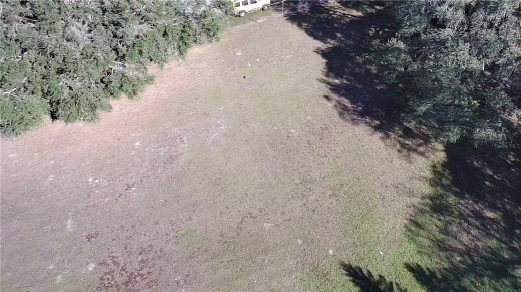 An aerial view shows a grassy, rectangular lot bordered by trees and a fence — 0 6TH STREET, MULBERRY, FL