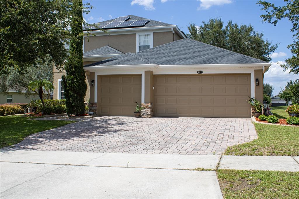 A two-story house with a three-car garage, paver driveway, and solar panels on the roof — 1112 GLENRAVEN LANE, CLERMONT, FL