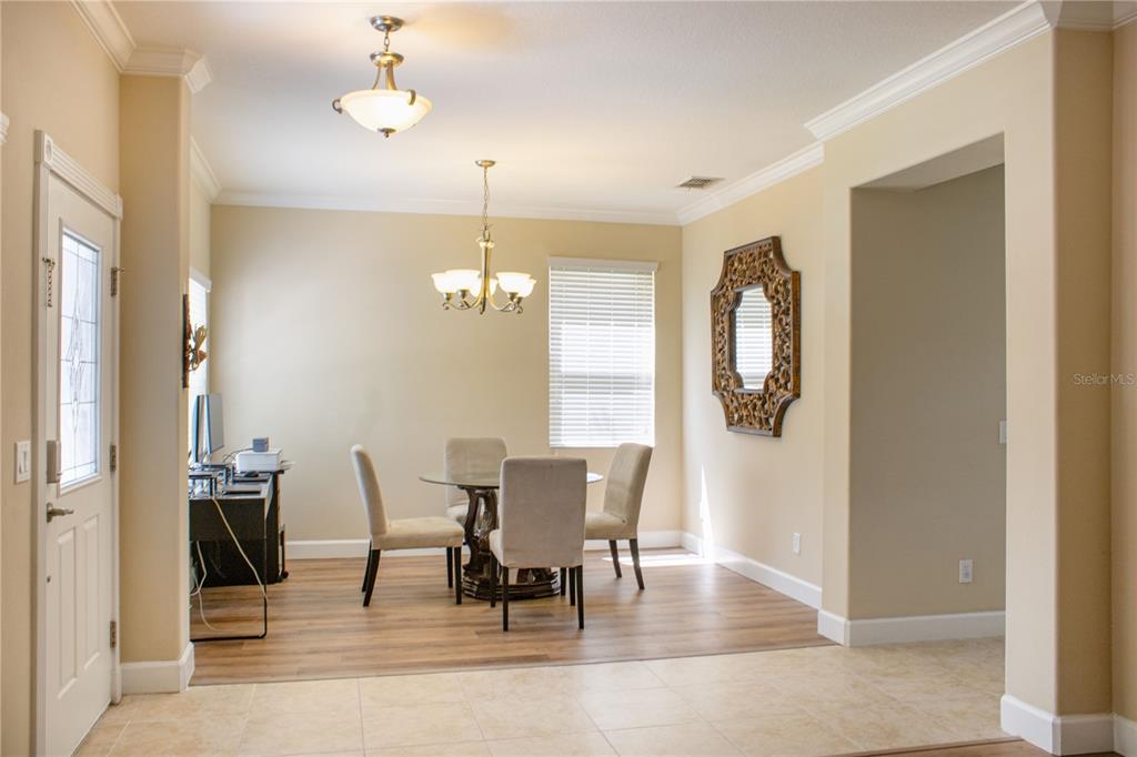 A dining area features a glass-top table, four upholstered chairs, and a decorative wall mirror — 1112 GLENRAVEN LANE, CLERMONT, FL