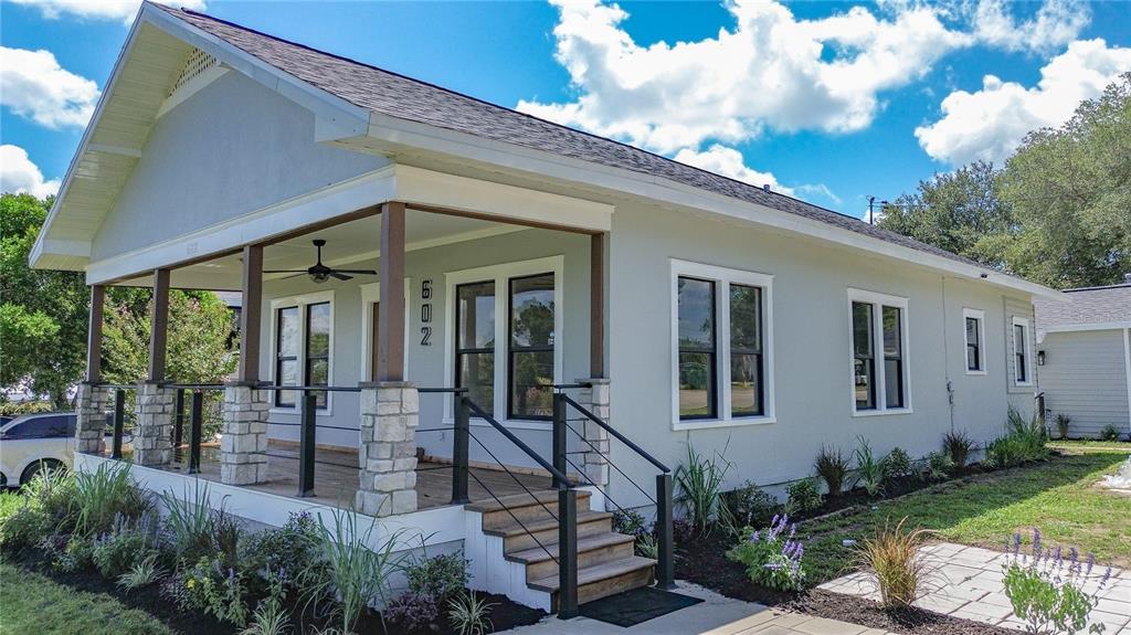 A light gray house features a front porch with stone pillars and a metal railing — 602 EDMUND AVENUE, DUNDEE, FL