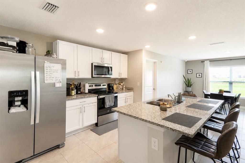A kitchen features white cabinets, stainless steel appliances, granite countertops, and a large center island — 37093 SHARKS EYE LANE, ZEPHYRHILLS, FL