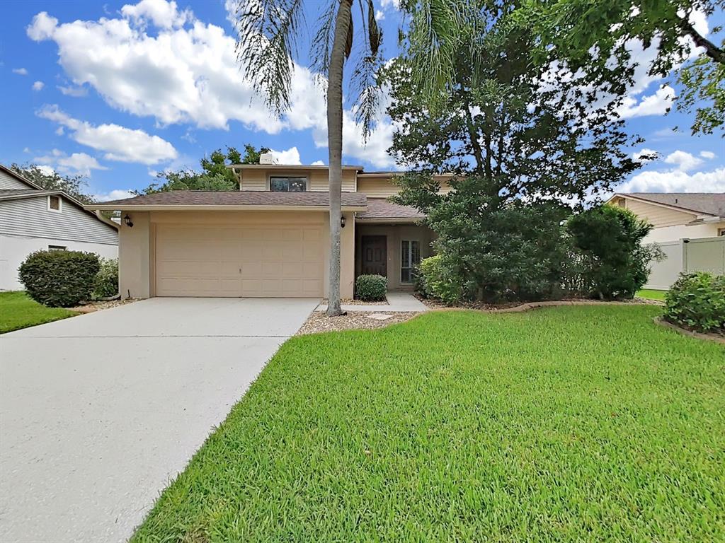 A two-story house with a beige exterior, a two-car garage, and a front lawn — 1367 CORNER OAKS DRIVE, BRANDON, FL