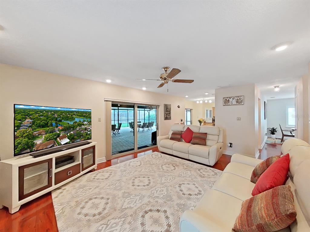 A living room features a white sofa, a large area rug, and a sliding glass door — 1367 CORNER OAKS DRIVE, BRANDON, FL