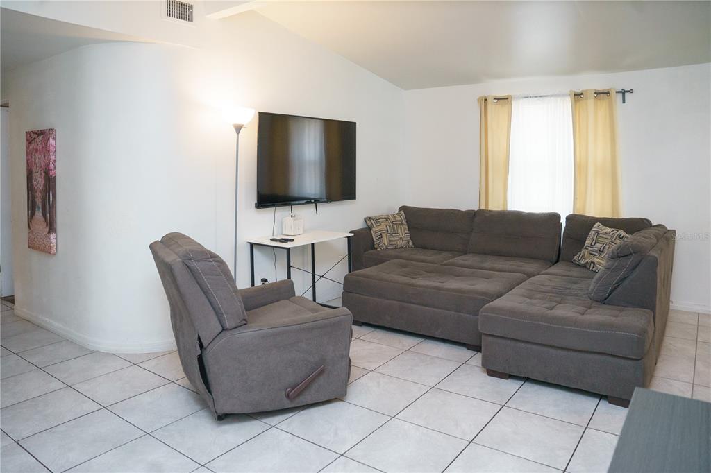 A living room features a gray sectional sofa, a matching recliner, and a wall-mounted television — 2804 N 33RD STREET, TAMPA, FL