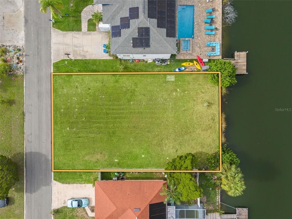 An aerial view shows a vacant, rectangular waterfront lot situated between two existing residential properties — 0 HIBISCUS DRIVE, HERNANDO BEACH, FL