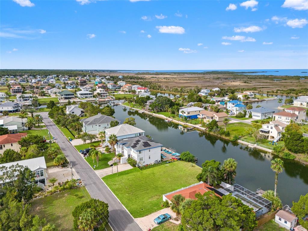 An aerial view shows houses along a canal leading toward a distant body of water — 0 HIBISCUS DRIVE, HERNANDO BEACH, FL