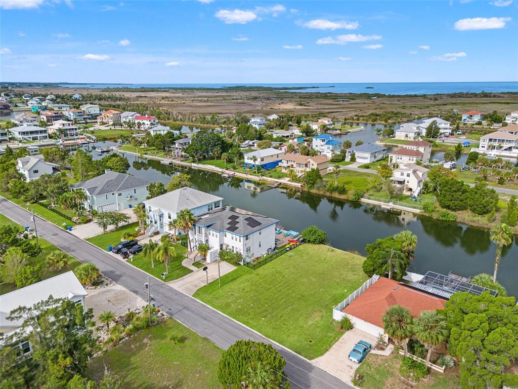 An aerial view shows waterfront houses along a canal leading to a large body of water — 0 HIBISCUS DRIVE, HERNANDO BEACH, FL