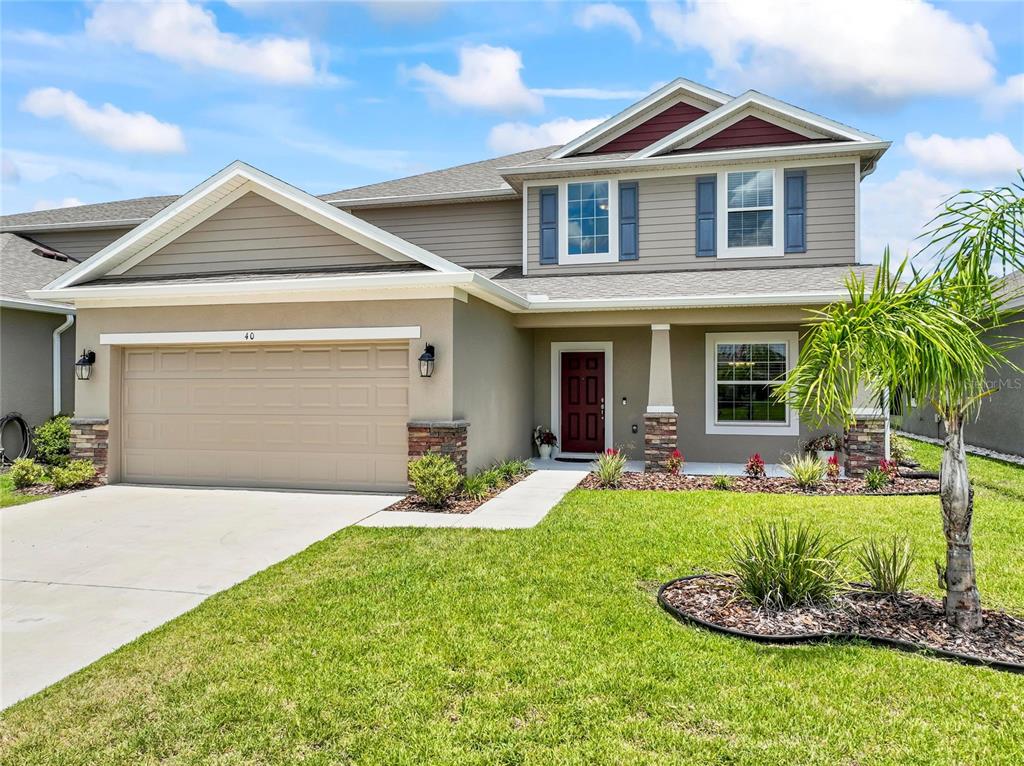 A two-story suburban house with a tan garage, gray siding, and a red front door — 40 OAKLEAF WAY, PALM COAST, FL