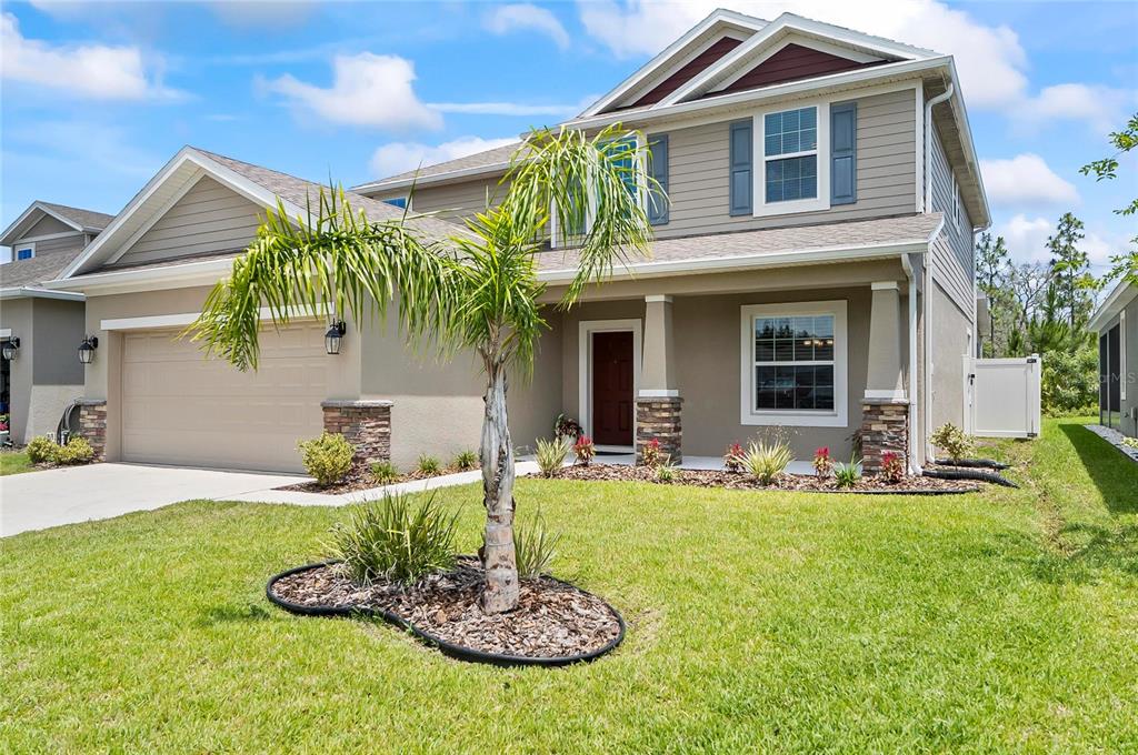 A two-story suburban house with a tan stucco exterior, a palm tree, and a garage — 40 OAKLEAF WAY, PALM COAST, FL