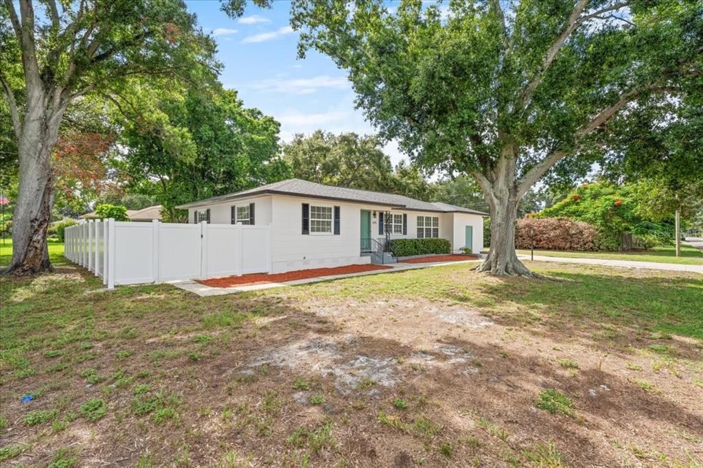 A single-story white house with black shutters and a white vinyl fence sits on a lot — 125 61ST STREET N, ST PETERSBURG, FL