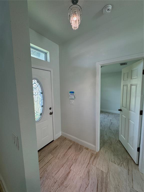 An entryway features a white front door with a glass insert, tile flooring, and a chandelier — 2452 AINSWORTH AVENUE, DELTONA, FL