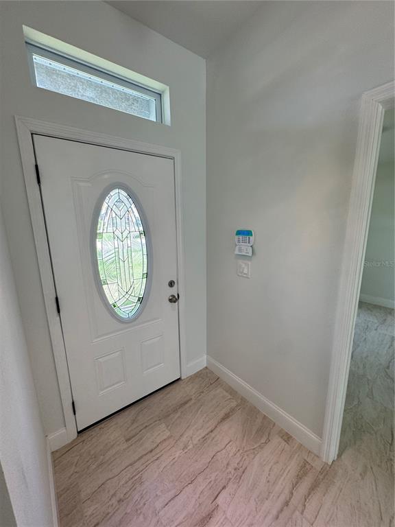An entryway features a white front door with a decorative oval glass insert and tile flooring — 2452 AINSWORTH AVENUE, DELTONA, FL