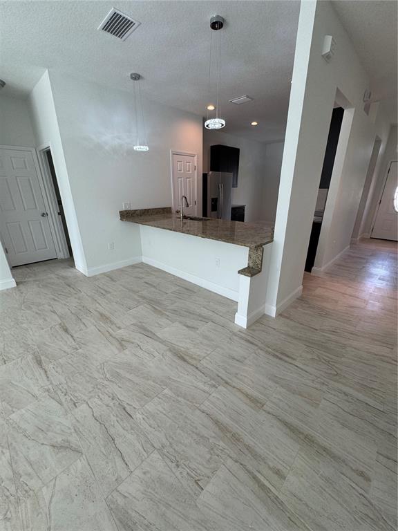 A kitchen features a granite breakfast bar, pendant lighting, and light-colored tile flooring — 2452 AINSWORTH AVENUE, DELTONA, FL