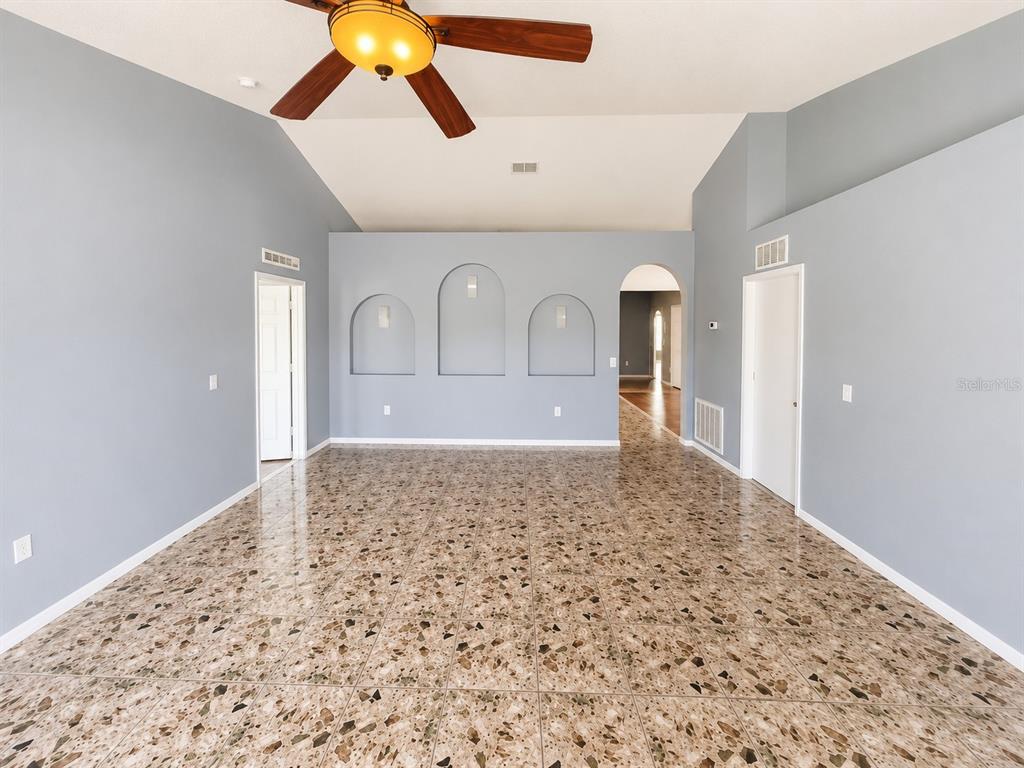 A living room with light blue walls, terrazzo flooring, a ceiling fan, and arched niches — 309 ALEGRIANO COURT, KISSIMMEE, FL