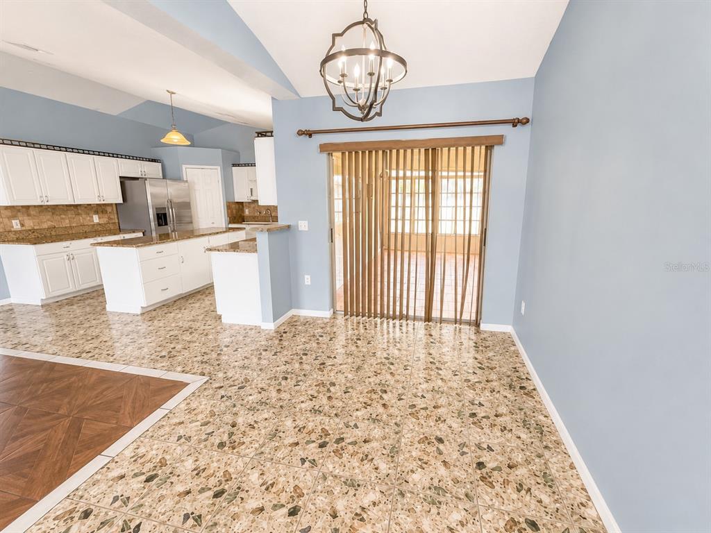 A kitchen and dining area with terrazzo flooring, white cabinetry, and a sliding glass door — 309 ALEGRIANO COURT, KISSIMMEE, FL