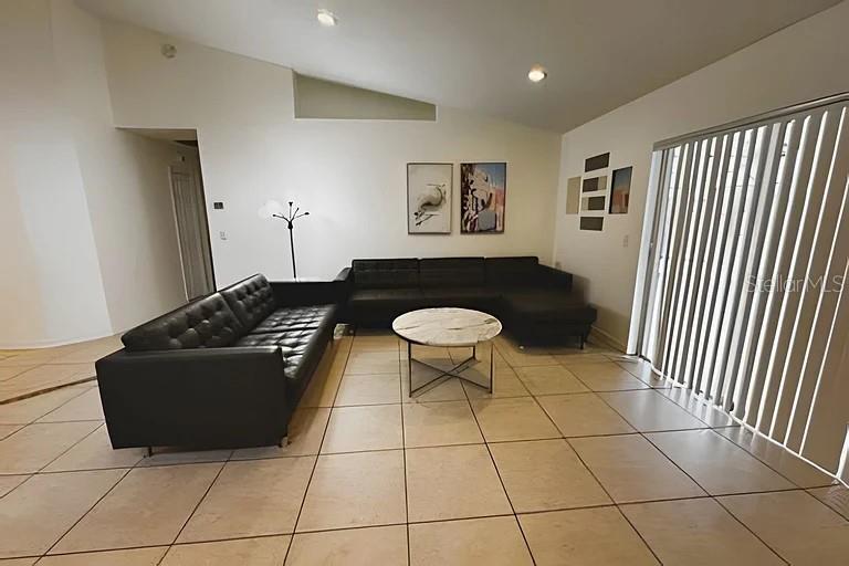 A living room features a black sectional sofa, a round coffee table, and tile flooring — 3129 BEAR PATH, KISSIMMEE, FL