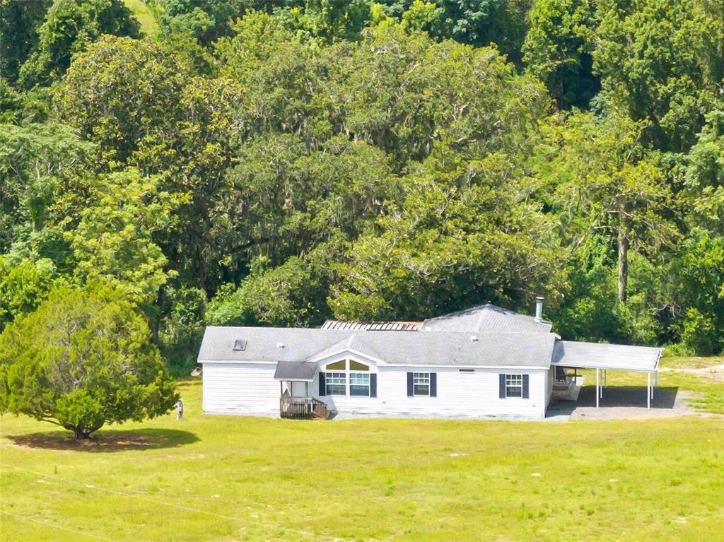 An aerial view of a white single-story house with a carport situated on a lawn — 33320 LARKIN ROAD, DADE CITY, FL