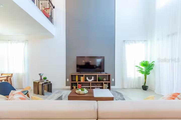 A living room features a tall gray accent wall, a television console, and white curtains — 2924 PROTAGONIST STREET, KISSIMMEE, FL