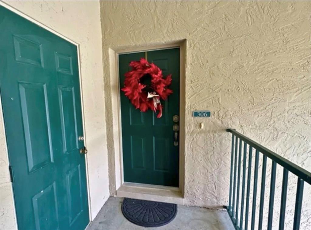 A teal front door with a red wreath and unit number 306 on a stucco wall — 306 EAGLE POND DRIVE, WINTER HAVEN, FL