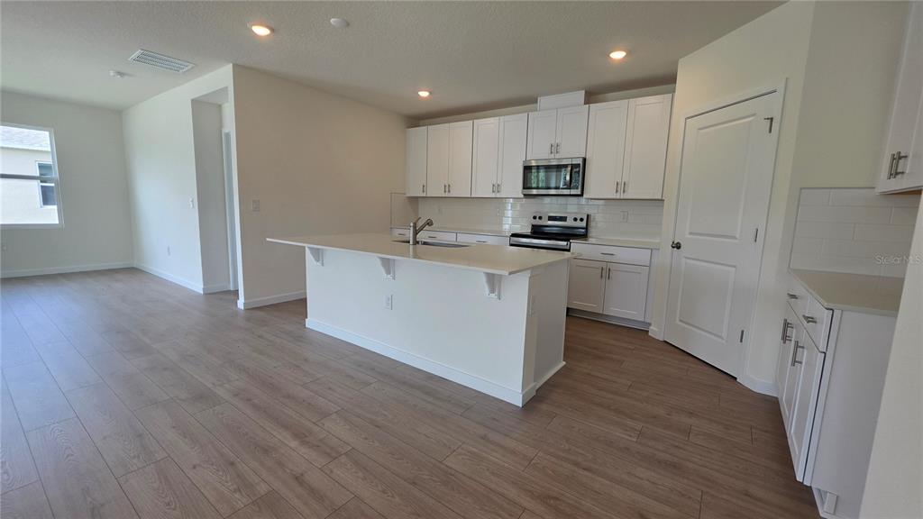 A bathroom features a white vanity with a single sink, a toilet, and a window — 5851 COOL SPRING COVE, ST CLOUD, FL