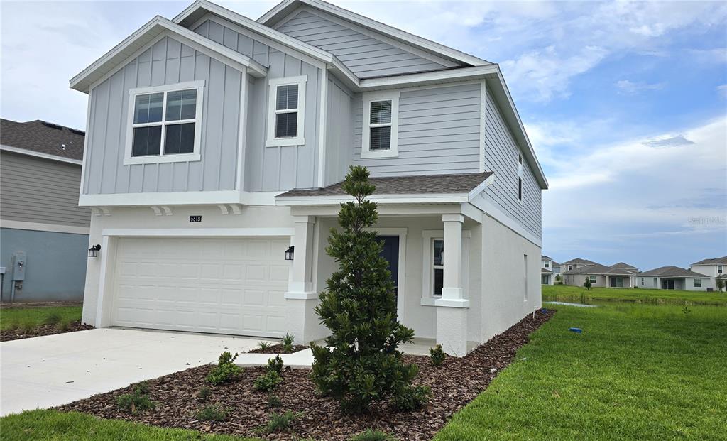 A two-story house with light gray siding, a two-car garage, and a small front yard — 5618 GINGHAM DRIVE, KISSIMMEE, FL