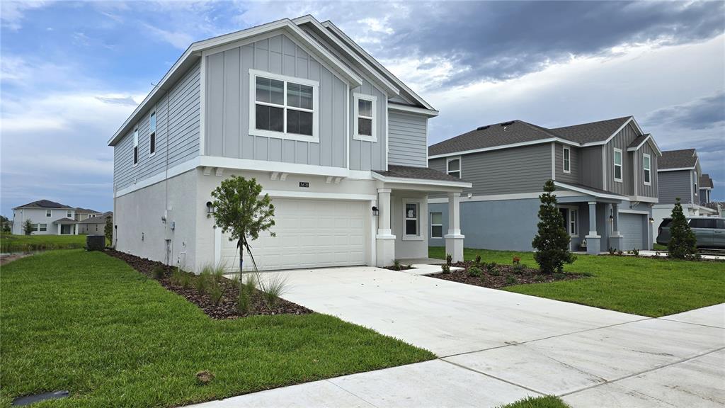 A two-story house with light gray siding and a white garage sits on a lawn — 5618 GINGHAM DRIVE, KISSIMMEE, FL