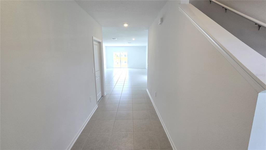A tiled hallway leads toward a bright living area with a staircase on the right — 5618 GINGHAM DRIVE, KISSIMMEE, FL