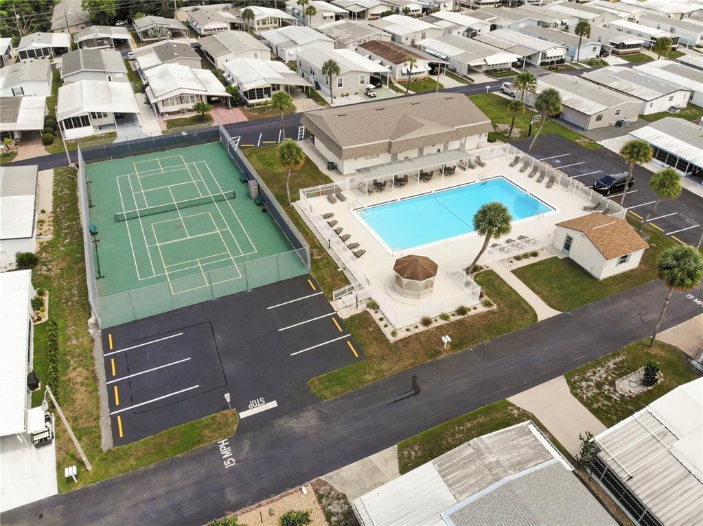 An aerial view shows a community tennis court, swimming pool, and clubhouse surrounded by mobile homes — 4332 CHERRYWOOD STREET, WINTER HAVEN, FL