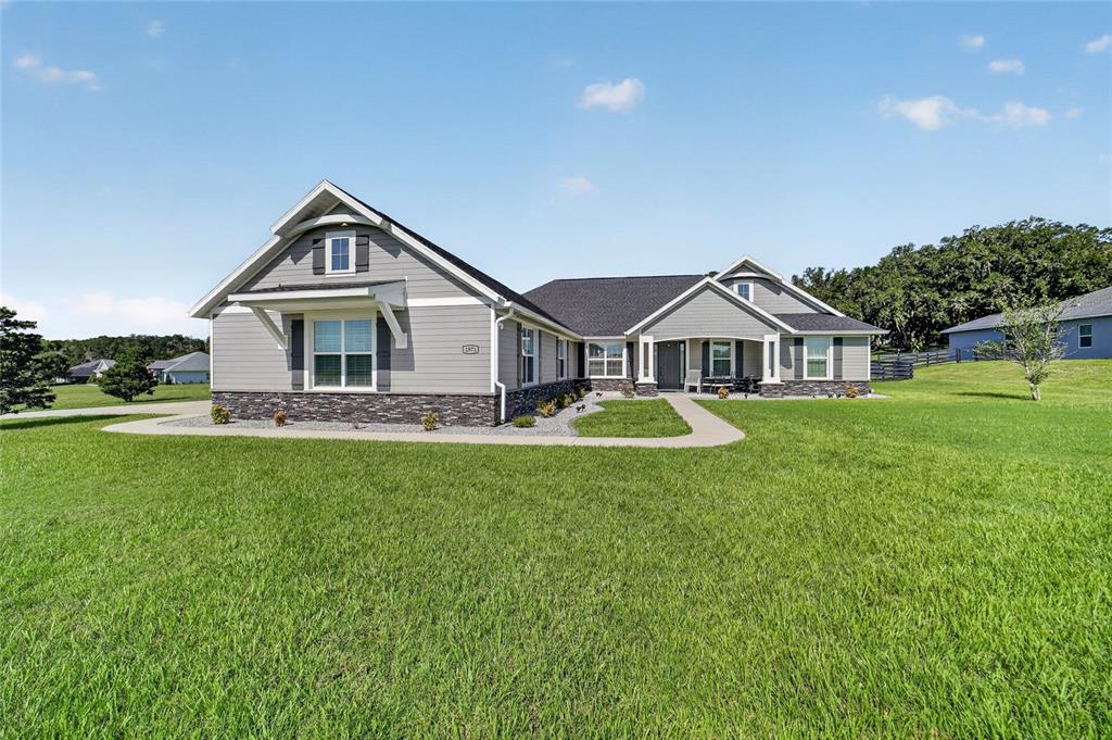 A single-story gray house with stone accents sits on a large, grassy lawn — 1971 NW 86TH PLACE, OCALA, FL