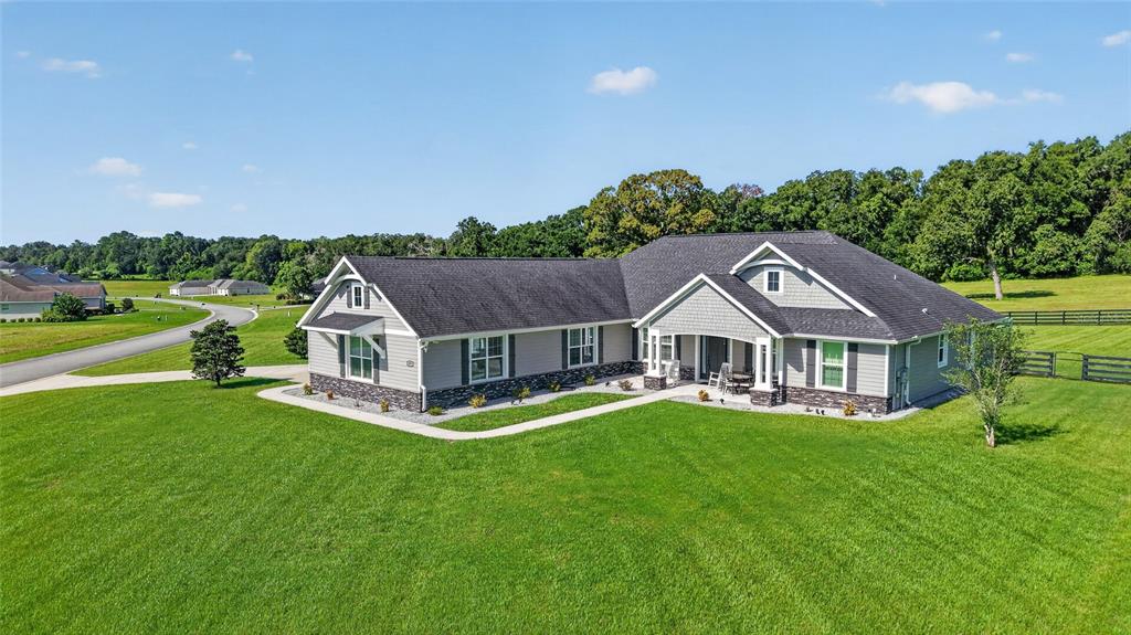 A single-story house with gray siding and a stone base sits on a grassy lawn — 1971 NW 86TH PLACE, OCALA, FL